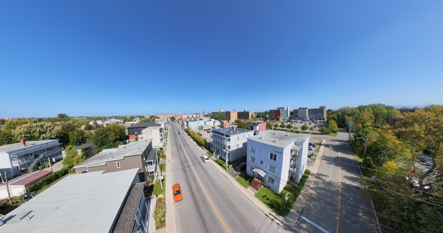Vue aérienne d'une avenue bordée d'immeubles à logements, sous un ciel bleu